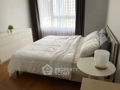 Cozy bedroom with modern decor, featuring a comfortable bed, stylish dresser, and natural light from large window.