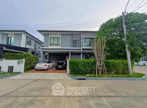 Modern two-story house with driveway and lush greenery in a suburban neighborhood.