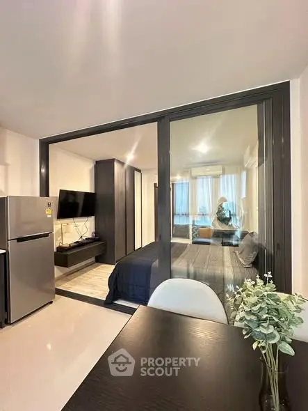 Modern open-plan apartment with glass partition, sleek kitchen, and cozy living area.