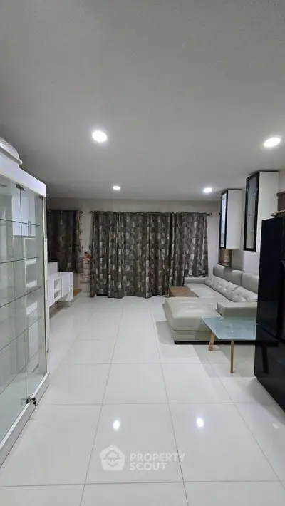 Spacious modern living room with sleek white tiles and elegant furnishings.