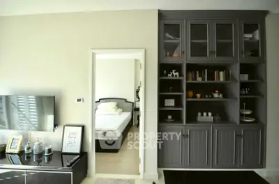 Chic living room with built-in shelving and cozy bedroom view, perfect for modern living.
