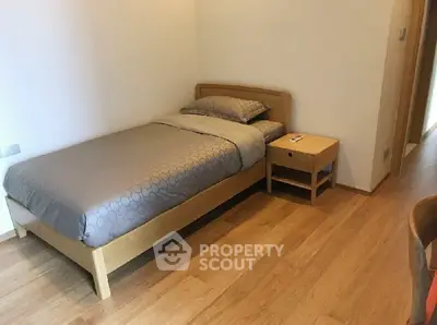 Cozy minimalist bedroom with wooden flooring and single bed, perfect for a serene retreat.