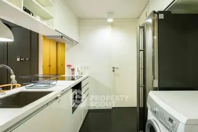 Modern kitchen with sleek appliances and washing machine in compact layout.