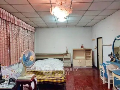 Spacious bedroom with vintage decor and wooden flooring, featuring a large bed and classic furniture.