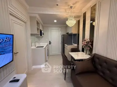 Modern living room with elegant chandelier and open kitchen layout in stylish apartment.