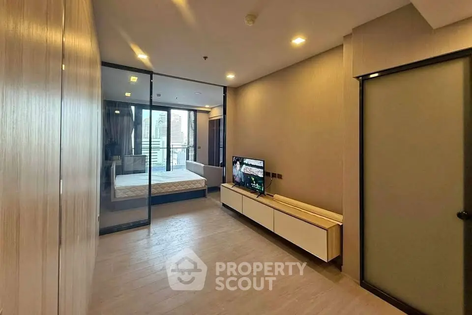 Modern apartment interior with sleek design and spacious layout, featuring a glass partition and stylish furnishings.