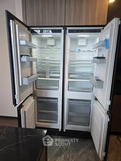 Spacious modern kitchen with double-door refrigerator and sleek cabinetry.