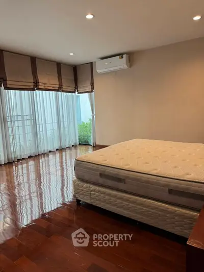 Spacious bedroom with large windows and polished wooden floors