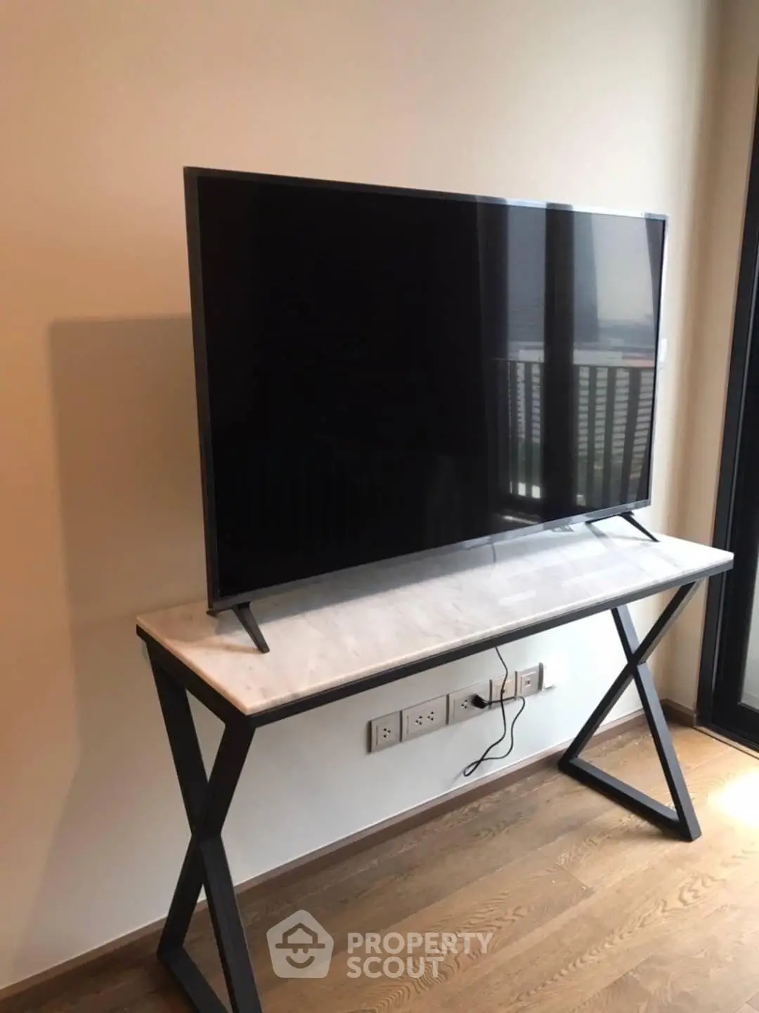 Modern living room with sleek TV on stylish console table, wooden flooring, and natural light.