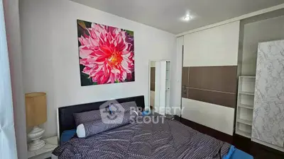 Modern bedroom with stylish decor and large floral artwork, featuring a cozy bed and ample storage space.