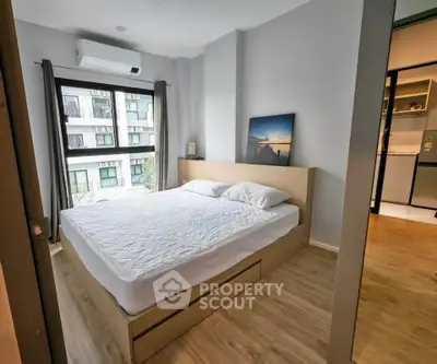 Modern bedroom with large window and wooden flooring in a stylish apartment.