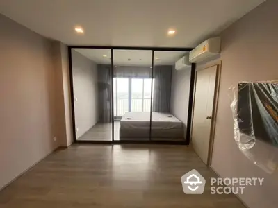 Modern bedroom with glass partition and air conditioning, featuring a minimalist design and wooden flooring.