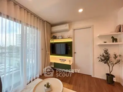 Modern living room with stylish decor, large window, and mounted TV in a cozy apartment setting.