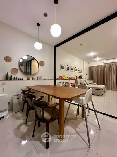 Modern dining area with wooden table and chairs, adjacent to spacious living room.