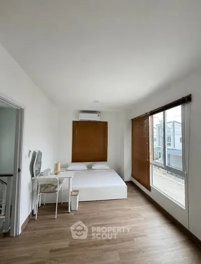 Spacious bedroom with modern decor and large window offering natural light.