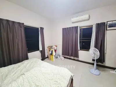 Cozy bedroom with air conditioning and fan, featuring large windows and neutral decor.