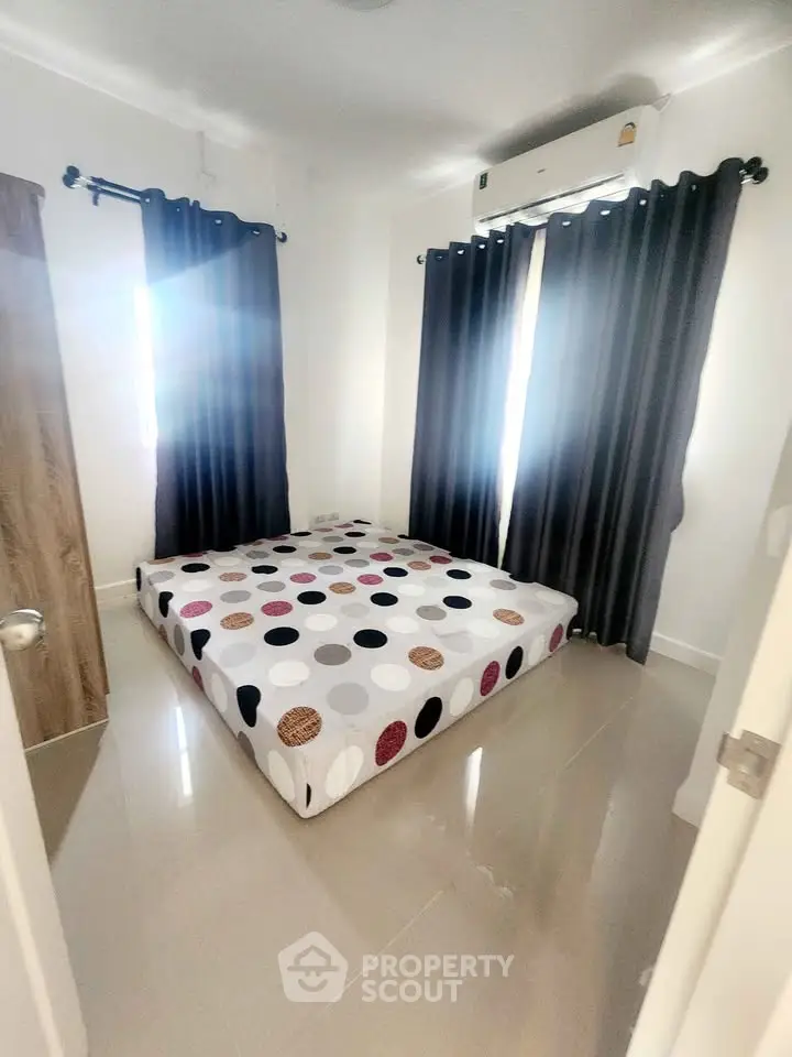 Cozy bedroom with modern decor and air conditioning, featuring a stylish bed and elegant curtains.