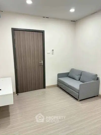 Minimalist living room with modern sofa and wooden door, perfect for cozy urban living.