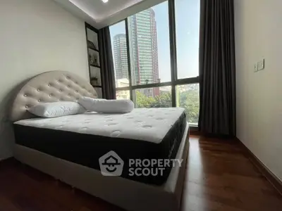 Luxurious bedroom with large window offering stunning city views and elegant decor.