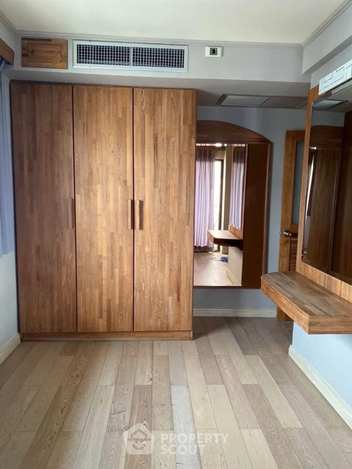 Spacious bedroom with wooden wardrobe and elegant mirror in modern apartment.