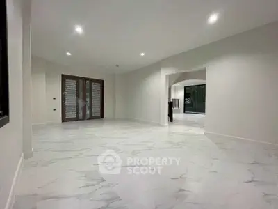 Spacious modern living room with elegant marble flooring and large windows.