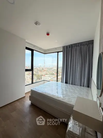 Spacious bedroom with large windows offering stunning city views, featuring modern decor and ample natural light.