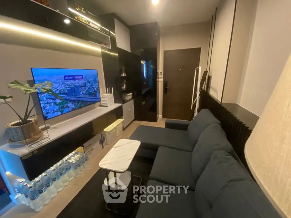 Modern living room with sleek black furniture and wall-mounted TV, showcasing a cozy and stylish interior design.