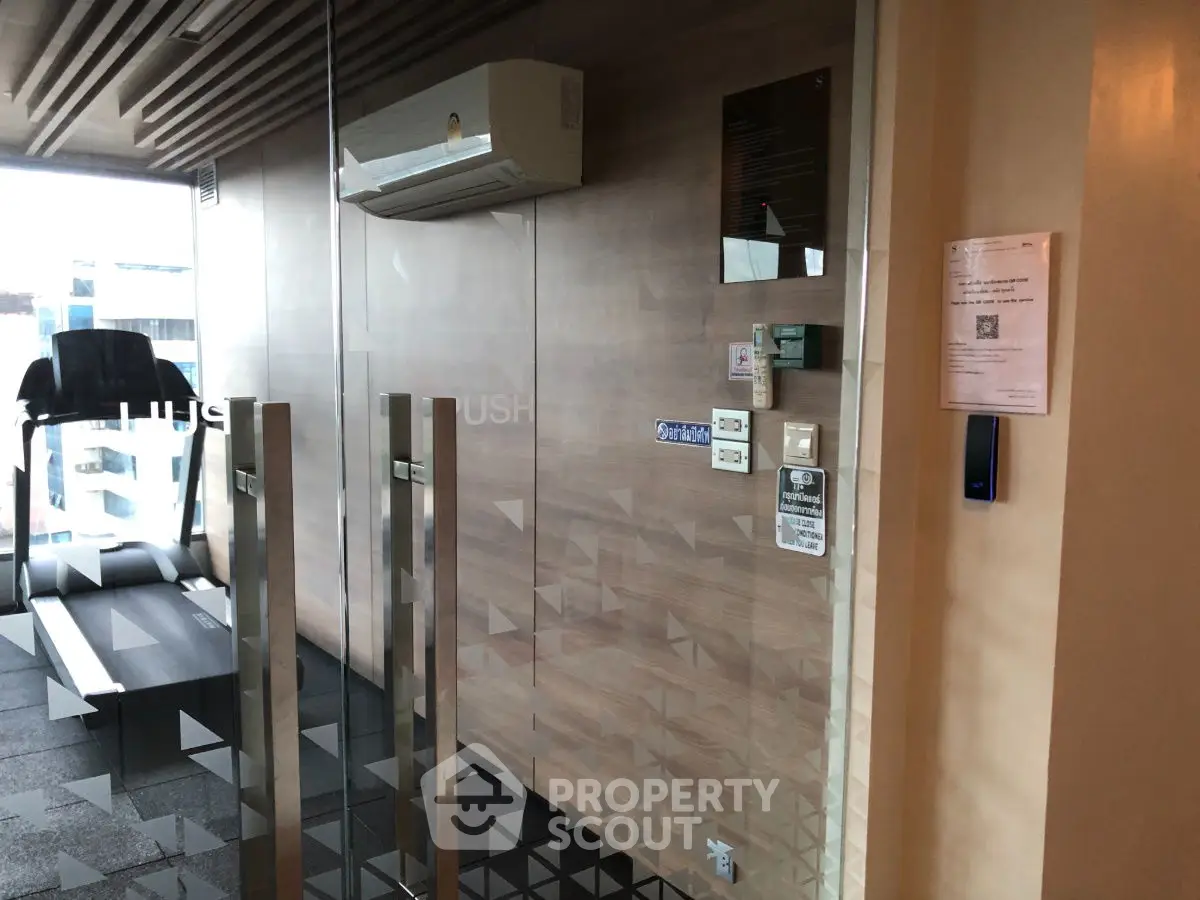 Modern gym entrance with glass doors and treadmill, sleek design