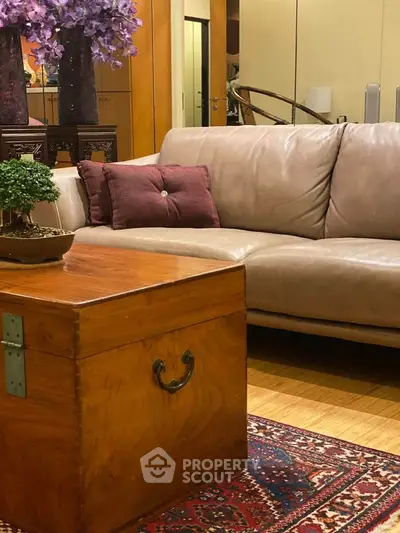 Elegant living room with plush sofa, wooden chest coffee table, and decorative plants on a patterned rug.