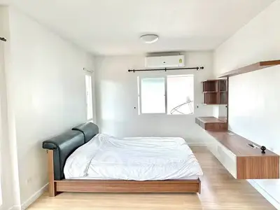 Spacious minimalist bedroom with modern wooden bed and wall-mounted shelves.
