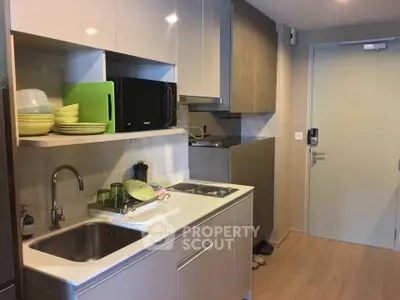 Modern compact kitchen with sleek cabinetry and built-in appliances in a cozy apartment.
