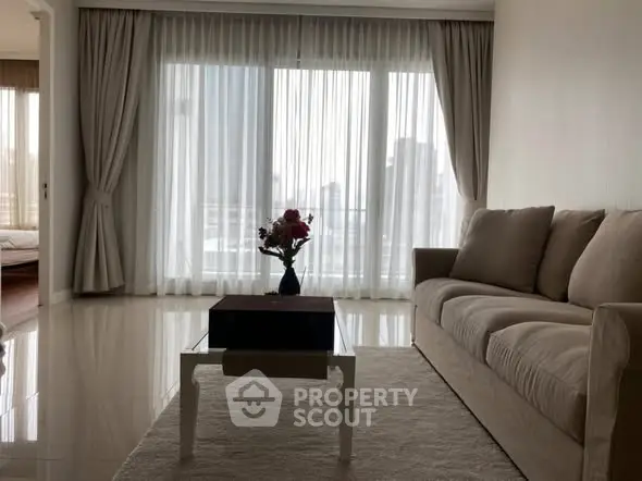 Elegant living room with plush sofa and city view through large windows.