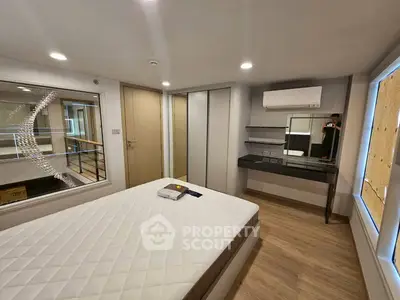 Modern bedroom with stylish decor and large mirror, featuring a comfortable bed and sleek wooden flooring.