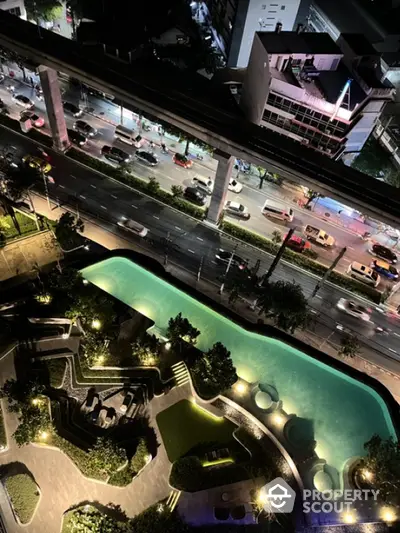 Stunning aerial view of illuminated pool and cityscape at night, perfect for urban living enthusiasts.