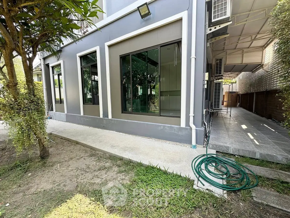 Modern house exterior with large windows and garden area, showcasing sleek design and outdoor space.