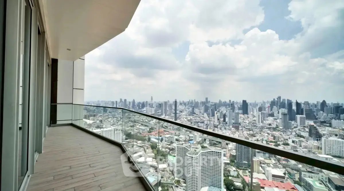 Stunning cityscape view from a spacious high-rise balcony with glass railing.