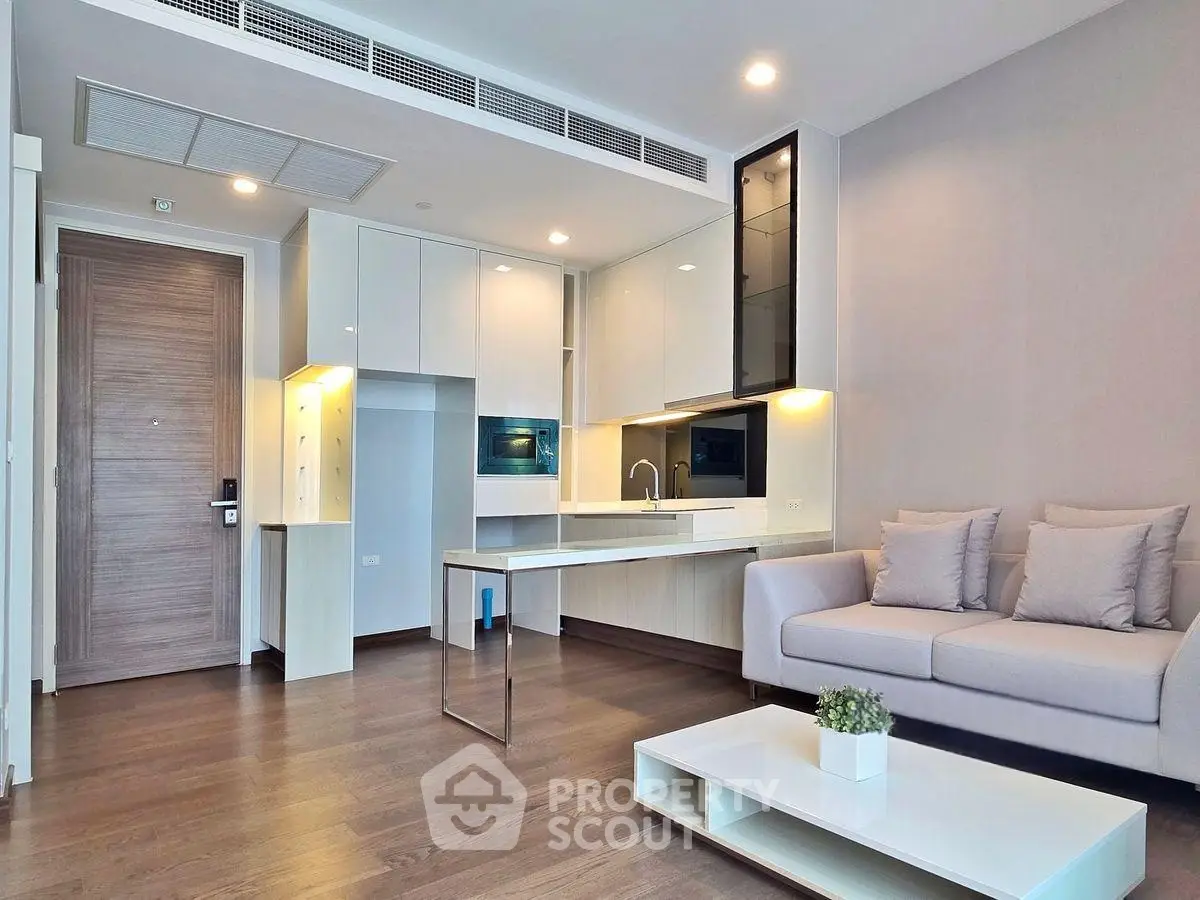 Modern living room with sleek kitchen and cozy sofa in open layout apartment.