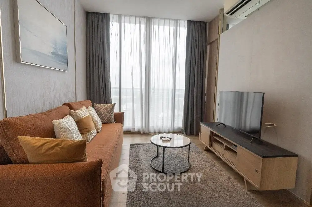 Modern living room with cozy sofa, stylish decor, and large window offering natural light.