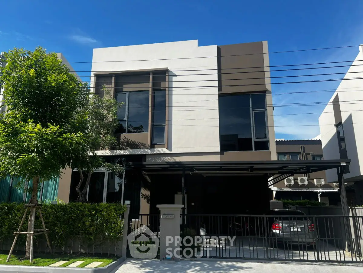Modern two-story house with sleek design and spacious driveway in a suburban neighborhood.