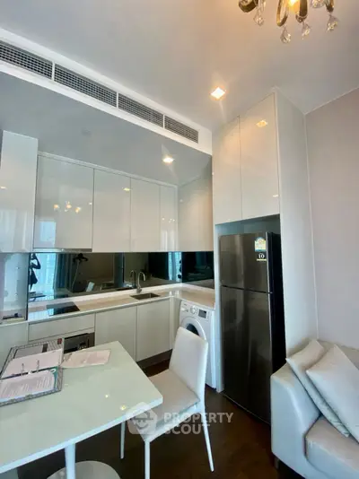 Modern kitchen with sleek cabinetry, stainless steel fridge, and integrated washing machine.