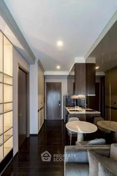 Modern apartment interior with sleek kitchen and cozy living area, featuring elegant lighting and contemporary design.
