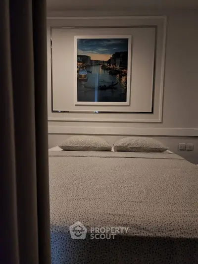 Cozy bedroom with elegant decor and framed artwork above the bed, perfect for relaxation.