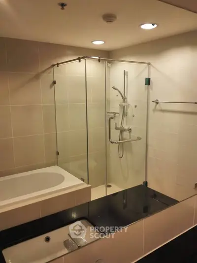 Modern bathroom with glass shower and bathtub in elegant real estate property.
