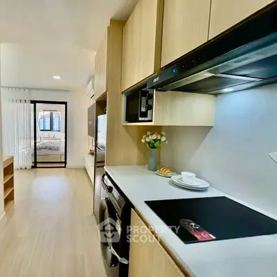 Modern kitchen with sleek appliances and open layout leading to a cozy bedroom.
