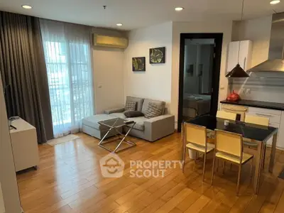 Modern living room with open kitchen, featuring sleek furniture and natural light.