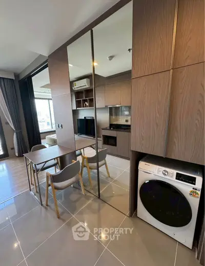 Modern apartment interior with sleek kitchen and dining area, featuring built-in appliances and stylish furniture.