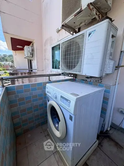 Compact balcony with washing machine and air conditioning unit, ideal for urban living.