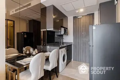 Compact modern kitchen with sleek appliances and dining area, featuring a washing machine, fridge, and microwave, ideal for urban living.