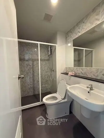 Modern bathroom with glass shower and sleek fixtures in contemporary apartment.