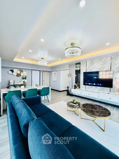 Luxurious modern living room with elegant decor and stylish furniture, featuring a plush blue sofa and chic lighting.
